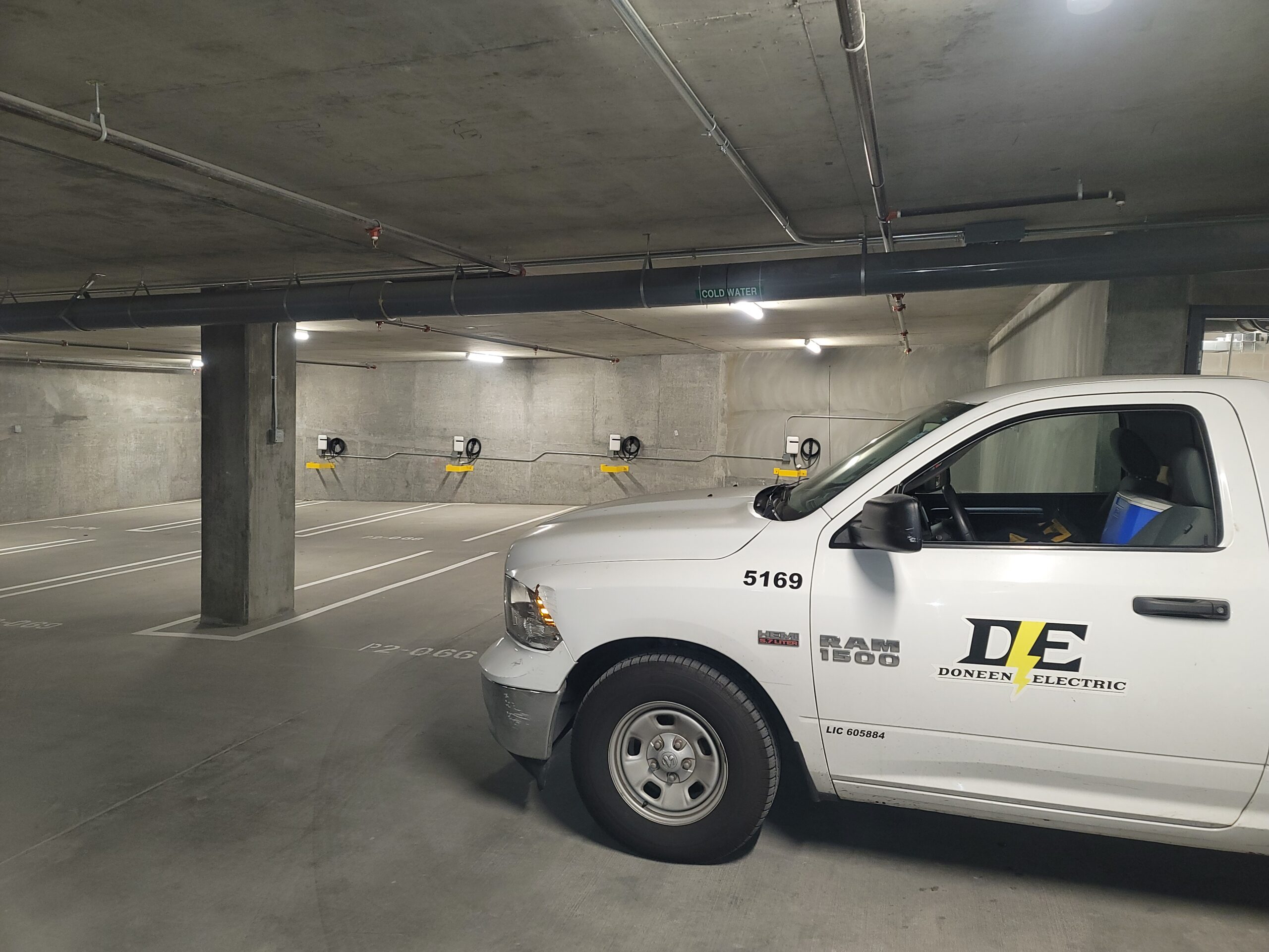 A white Doneen Electric RAM 1500 truck in an empty underground parking.